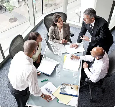 Rental coordinators comparing vehicle availability and quotes around a meeting table